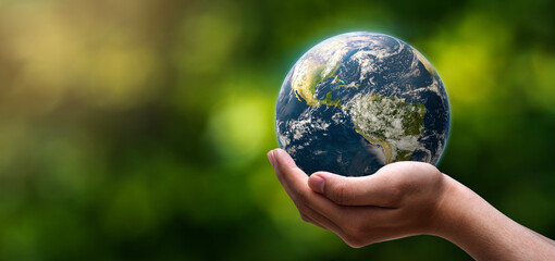 globe blue on hands in green blurred nature background, earth in adult hands , earth day, world day,