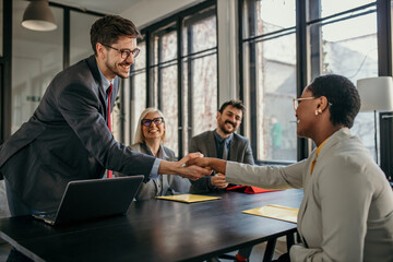 Wall Mural - Smiling businessman shaking hand with new client in a modern office