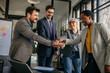 © La Famiglia - Group of diverse businesspeople holding hands together, united in new projects and ideas while standing in the bright office.