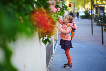 Wall Mural - preschooler girl with school backpack having fun on a street on a fall day