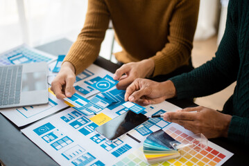  UX developer and ui designer brainstorming about mobile app interface wireframe design with customer breif and color code at modern office.
