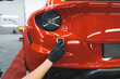 © PoppyPix - Car detailing process. Beautiful red sports car's paint being wrapped with transparent vehicle vinyl foil. Back indoor shot. High quality photo