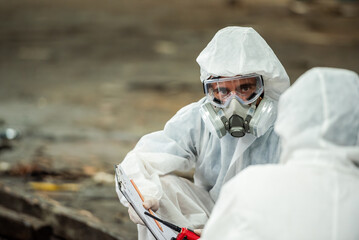 Male inspector team investigate danger chemical gas leak spill with safety face mask PPE suit in area closed barricade security tape. danger dirty area infected chemical leak spill cross stripe ribbon