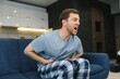 © Serhii - Young man suffering from stomach ache at home