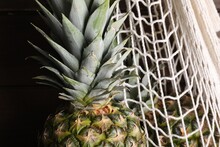 Whole Ripe Pineapples And Net Bag, Closeup