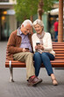 © Degimages - Elderly couple sitting together on a park bench and watching its mobile phones