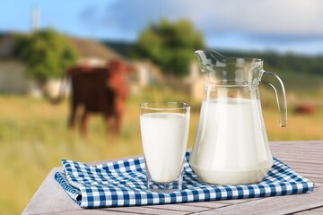 Poster - Tasty fresh milk on wooden table in meadow