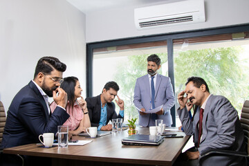 Stress situation in conference room, indian boss unhappy with the performance of his employees for doing doing bad work.