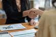 © crizzystudio - Two asian businesswoman shaking hands in modern office after success in financial business Documents investing in teamwork and friendship. startup business ideas real estate project.