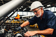 © mikhailberkut - Digital portrait of a senior successful confident professional Aerospace engineer is assembling an aircraft engine in a Plane assembly line. Concept of active age. Generative AI
