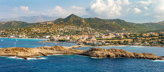 
panoramic view of the city of red island in corsica with the mediterranean sea and the mountains in the background on a sunny day