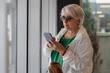 © ADDICTIVE STOCK - Senior woman using smartphone in hall
