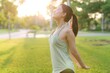 Female jogger. Fit young Asian woman with green sportswear breathing fresh air in park before running and enjoying a healthy outdoor. Fitness runner girl in public park. Wellness being concept
