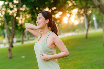 Female jogger. Fit young Asian woman with green sportswear stretching muscle in park before running and enjoying a healthy outdoor. Fitness runner girl in public park. Wellness being concept