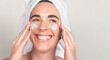 © ADDICTIVE STOCK - Happy woman with towel wrapped head applying cosmetic mask and cream