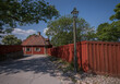 Old red wood bank house, red fence and lamp post in a park, a sunny summer day in Stockholm