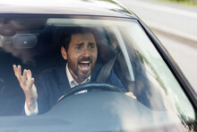 Angry Male Car Driver Yells At Other Drivers And Pedestrians Who Obstruct Traffic, Mature Adult Businessman In A Business Suit Is Late For A Business Meeting In A Car