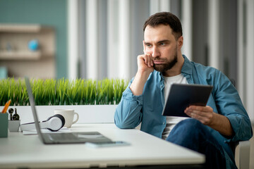Aufkleber - Inspiration Crisis. Bored Male Freelancer Holding Digital Tablet And Looking At Laptop