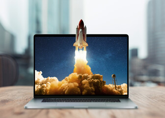 Space rocket shuttle with a cloud of smoke and blast takes off from a laptop on a working office desk. Creative idea and startup. Successful business project. Go outside the frame