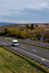 Wall Mural - White delivery van on the highway. White modern delivery small shipment cargo courier van moving fast on motorway road to city urban suburb. The world's best transport of goods.