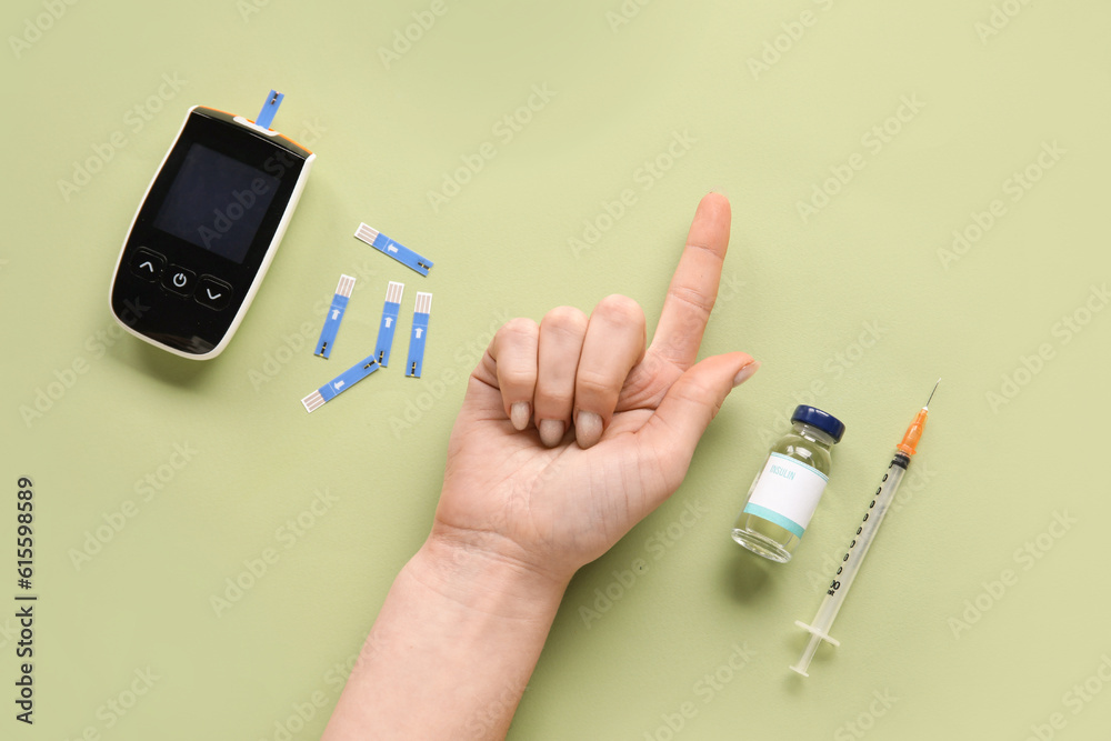 Diabetic woman with digital glucometer and insulin on green background