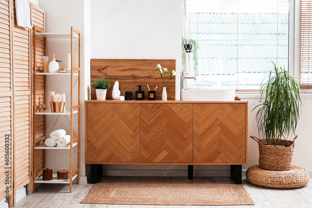 Interior of light bathroom with sink, drawers and shelving unit
