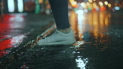 Wall Mural - close-up of a woman's feet stepping into a muddy puddle and making a splash