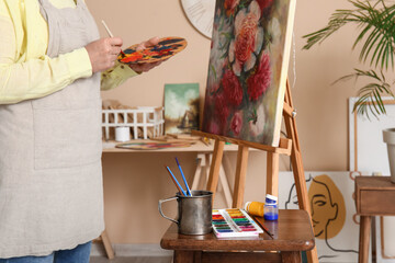 Wall Mural - Mature female artist painting picture in  workshop