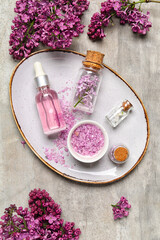 Wall Mural - Bottle of lilac essential oil, sea salt and flowers on grunge background