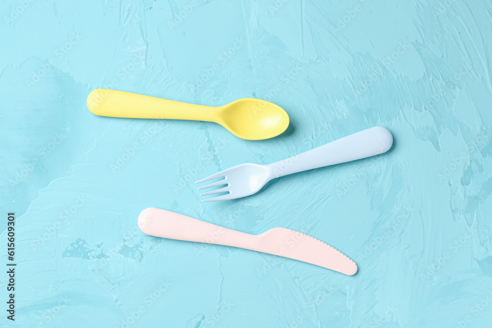 Colorful plastic cutlery for baby on grunge blue background
