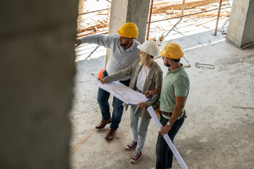 A female architect and construction manager work together on-site, discussing blueprints and coordinating to bring their project to life.