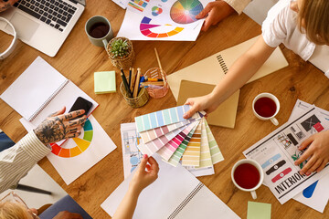 Team of graphic designers working with color palettes at table in office, closeup