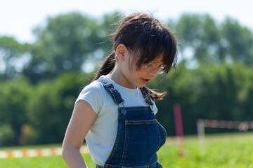 Wall Mural - Cute little girl walking in the field on a sunny summer day