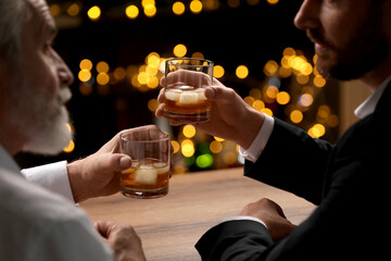 Wall Mural - Men with glasses of whiskey talking at wooden table in bar