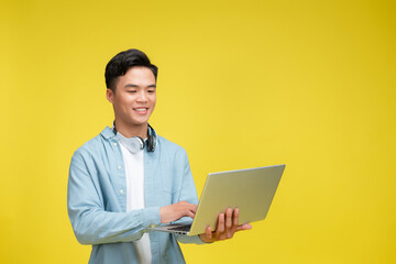 Wall Mural - Adult Asian man looking to the camera while holding a laptop and showing happy expression