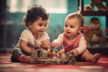 Smiling Babies Playing Together In A Play Room, Little Girl Babies Playing With Toys By The Home, Toddlers Sitting Playing With Toys, Preschool Boy And Girl Playing On Floor With Educational Toys