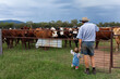 © Austockphoto - Middle aged farmer with toddler child watching cattle in paddock by old farm gate