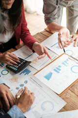Close up group of business men and woman discussion and brainstorming, bookkeeping audit graph and chart documents at desk, teamwork concept.