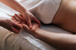 Close-up cropped shot of unrecognizable professional masseuse hands doing finger and palm massage to male client lying on massage table in spa salon. Woman physiotherapist doing relaxing massage man.