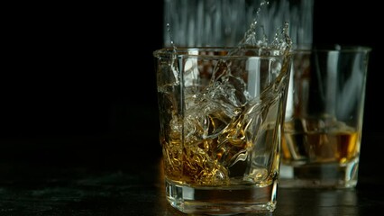 Wall Mural - Ice dropped into glass of whisky, dark background. Shot with high speed cinema camera, 1000fps.