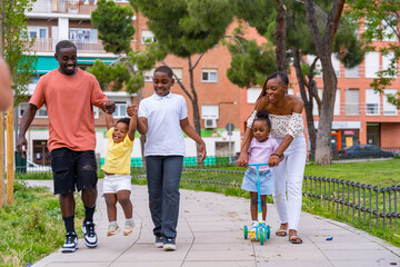 African black ethnicity family with children on playground, having fun in city park