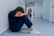 © makedonski2015 - A tired doctor is sitting on the floor in the hallway. The operation is long-term. In the background are colleagues at the clinic.