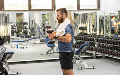 Man training in a gym ,Fitness man with dumbbell in gym. looking away