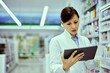 © bnenin - A pretty female pharmacist working over the digital tablet in a drugstore.
