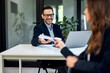 © bnenin - A smiling businessman taking a document from a female colleague at the office.