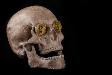 A gold coin with the Bitcoin cryptocurrency symbol in the eye sockets of a human skull 