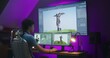 © Framestock - Young creative 3D designer creates video game character or animation, works remotely at home office. Computer and big digital screen with professional software interface for 3D modeling and design.