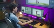 Young 3D designer draws video game character, creates animation. Teenager works remotely at home on computer and big digital screen with professional software interface for 3D modeling and design.