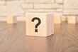 wooden blocks with question marks on wooden table, close up. space for text