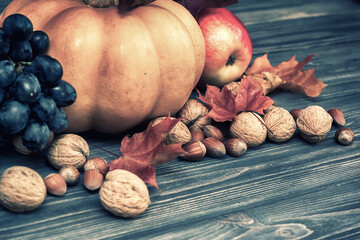 Canvas Print - Pumpkin, apple, nuts, berries with maple leaves on wooden background. Autumn card thanksgiving. Halloween. Vintage toned